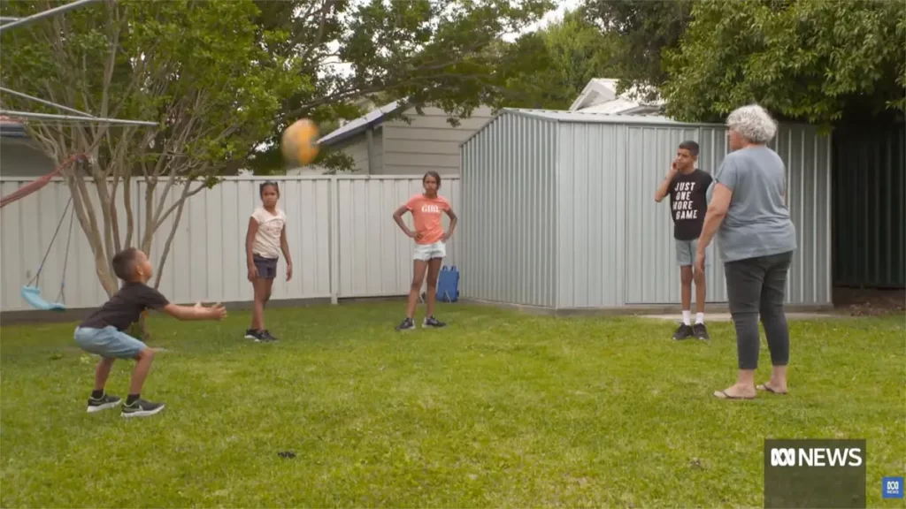 Kids playing backyard footy with grandmother