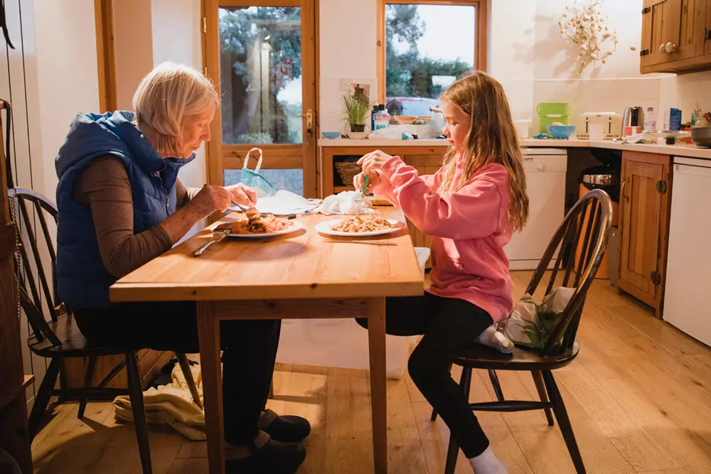 Grandmother sits at table with granddaughter